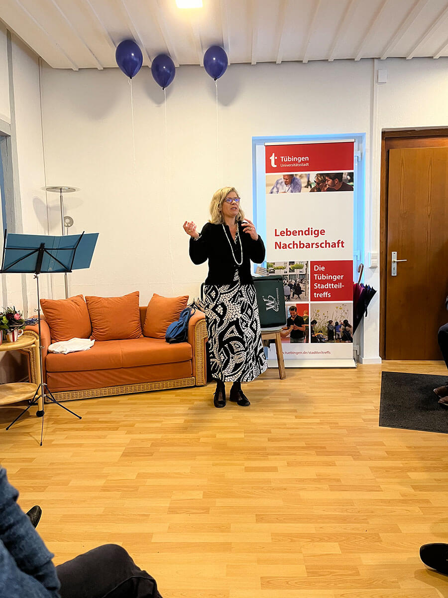 Blick vom Publikum auf eine Frau, die gestikulierend vor dem Sofa im Eingangsbereich steht