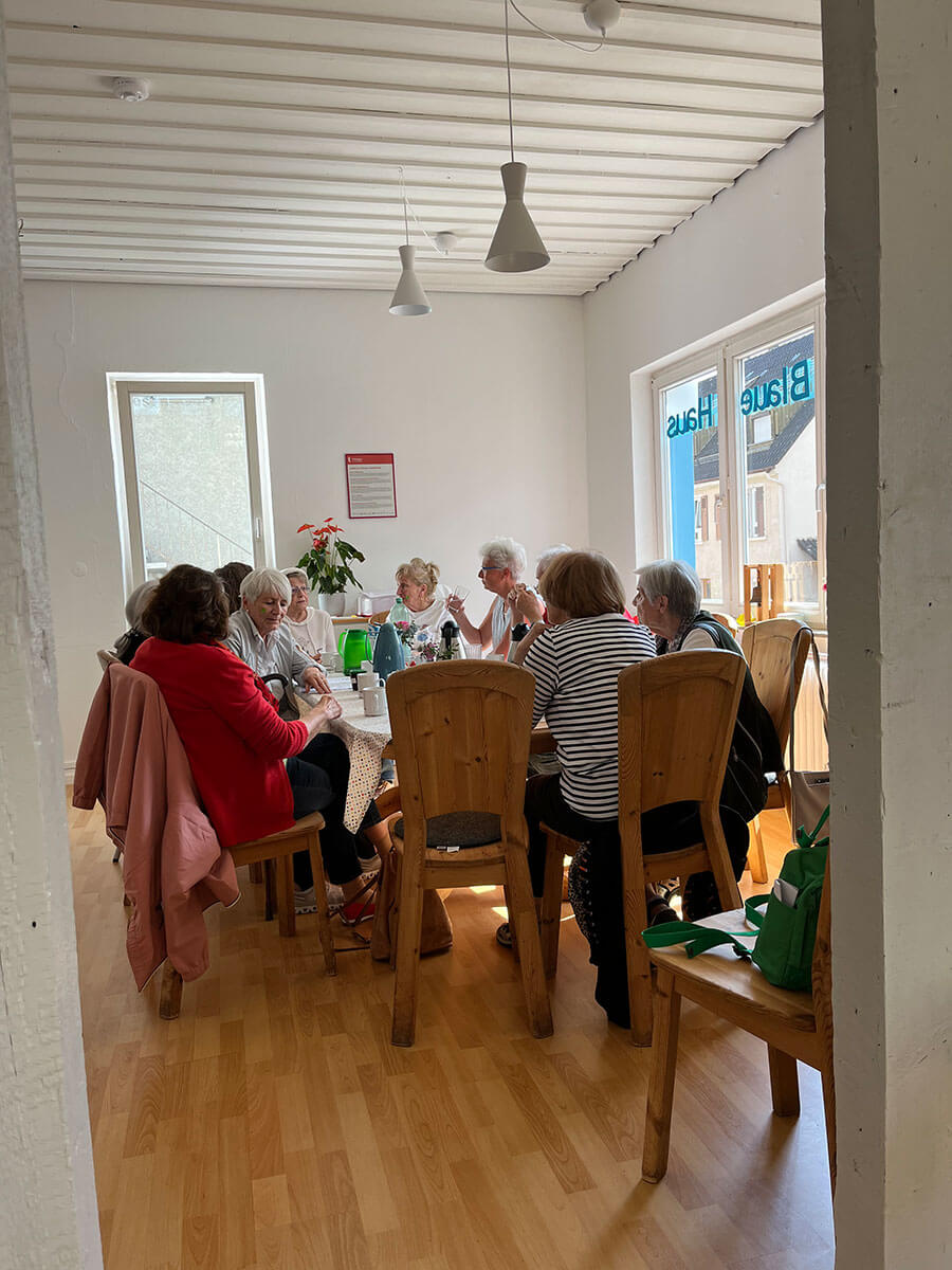 am großen Tisch bei der Küche sitzen viele Menschen gemütlich beisammen