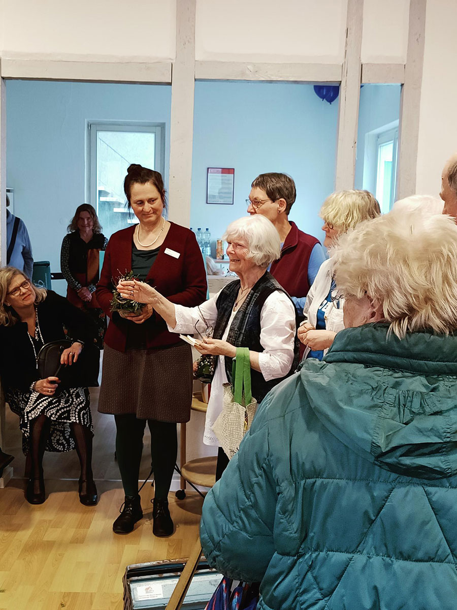 Blick aus dem Publikum auf eine ältere Frau umgeben von Leuten