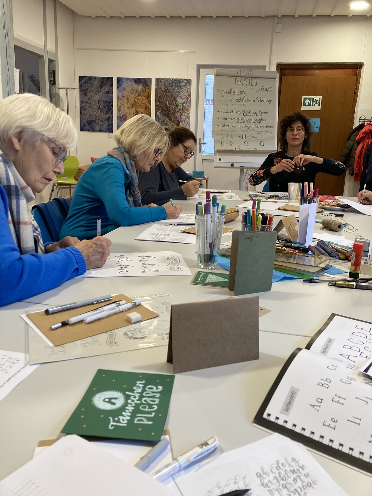 mehrere Frauen schreiben oder malen unter Anleitung